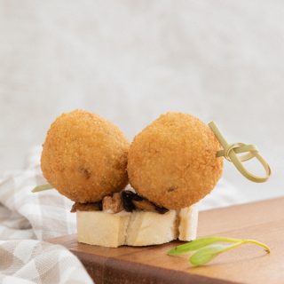 Brocheta de croquetas de puerro y setas sobre cama de champiñones